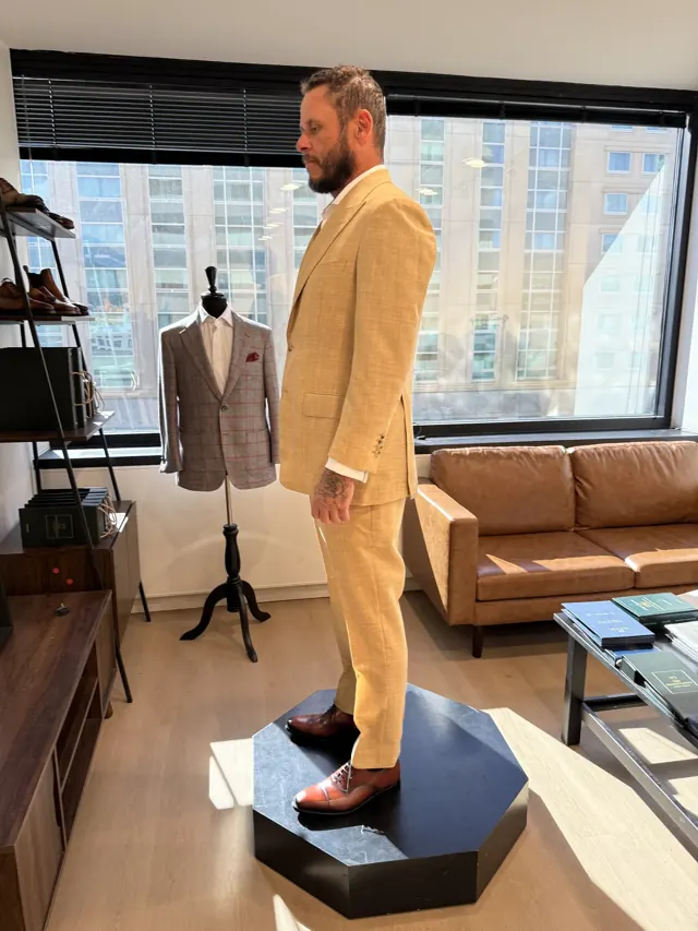 Client trying on a custom tan suit during a fitting