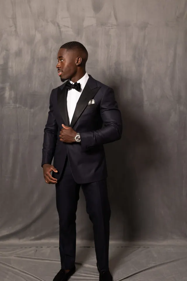 Kobe Apponsah in a midnight navy peak lapel tuxedo